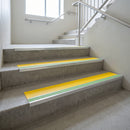 Photoluminescent aluminium stair nosing 56x55mm with yellow PVC insert fitted to a concrete stairwell, green glow strip along the nose