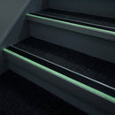 72x55mm photoluminescent stair nosing glowing green along each step edge in a dark stairwell during a power cut, no wiring or power needed