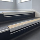Porth Stone Castellated insert in a 66x55mm square front aluminium stair nosing with 13mm black riser highlight, fitted to interior steps