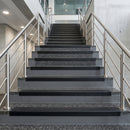 Black PVC hard nose stair nosings with black anti-slip inserts fitted to concrete steps in a commercial stairwell