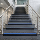 Black PVC hard nose stair nosings with cobalt blue anti-slip inserts fitted to concrete steps in a commercial stairwell