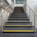 Black PVC hard nose stair nosings with yellow anti-slip inserts fitted to concrete steps in a commercial stairwell