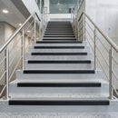 Black PVC hard nose stair nosings with cloud grey anti-slip inserts fitted to pale terrazzo steps in a commercial stairwell
