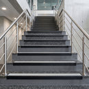 Black PVC hard nose stair nosings with haze pale grey anti-slip inserts fitted to concrete steps in a commercial stairwell