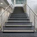 Black PVC hard nose stair nosings with sand anti-slip inserts fitted to terrazzo steps in a commercial stairwell