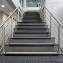 Black PVC hard nose stair nosings with beige anti-slip inserts fitted to concrete steps in a commercial stairwell