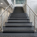 Black PVC hard nose stair nosings with black anti-slip inserts fitted to concrete steps in a commercial stairwell