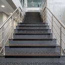 Black PVC hard nose stair nosings with brown anti-slip inserts fitted to concrete steps in a commercial stairwell