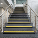 Black PVC hard nose stair nosings with yellow anti-slip inserts fitted to concrete steps in a commercial stairwell