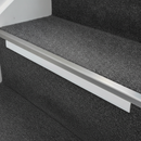 White anti-slip PVC stair nosing insert strip fitted into an aluminium stair nosing channel on a dark carpeted staircase