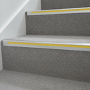 High-visibility yellow anti-slip PVC stair nosing insert strip fitted into an aluminium stair nosing channel on stairs