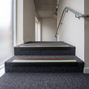 PVC stair nosing 60x32mm with brown anti-slip insert fitted to grey carpeted steps, green photoluminescent strip along the front edge