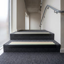 PVC stair nosing 60x32mm with canvas anti-slip insert fitted to grey carpeted steps, green photoluminescent strip along the front edge