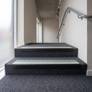 PVC stair nosing 60x32mm with dolphin grey anti-slip insert fitted to grey carpeted steps, green photoluminescent strip along the front edge