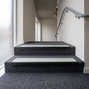 PVC stair nosing 60x32mm with ice grey anti-slip insert fitted to grey carpeted steps, green photoluminescent strip along the front edge