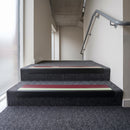 PVC stair nosing 60x32mm with red anti-slip insert fitted to grey carpeted steps, green photoluminescent strip along the front edge