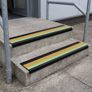 PVC stair nosing 60x32mm with yellow anti-slip insert fitted to external concrete steps, green photoluminescent strip along the front edge