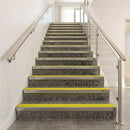 Full staircase of dark stone steps edged with yellow insert nosings, handrails on both sides