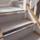 Rake back aluminium stair nosing with a dark charcoal Mor Grip insert in bright polished finish fitted on a domestic staircase finished in light grey carpet
