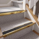 Rake back aluminium stair nosing with a dark charcoal Mor Grip insert in mirrorflect gold finish fitted on a domestic staircase finished in light grey carpet