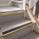 Rake back aluminium stair nosing with a dark charcoal Mor Grip insert in satin gold finish fitted on a domestic staircase finished in light grey carpet