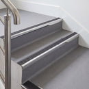 Rake back aluminium stair nosing with a dark charcoal Mor Grip insert in bright polished finish fitted on an office stair finished in grey lino