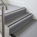 Rake back aluminium stair nosing with a dark charcoal Mor Grip insert in mill finish finish fitted on an office stair finished in grey lino