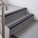Rake back aluminium stair nosing with a dark charcoal Mor Grip insert in satin black finish fitted on an office stair finished in grey lino