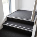 Rake back aluminium stair nosing with a dark charcoal Mor Grip insert in mill finish finish fitted on an office stairwell finished in charcoal contract carpet