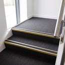 Rake back aluminium stair nosing with a dark charcoal Mor Grip insert in satin gold finish fitted on an office stairwell finished in charcoal contract carpet