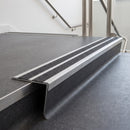 Rake back aluminium stair nosing with twin dark charcoal Mor Grip inserts in mill finish finish fitted on a college stair finished in dark grey sheet vinyl