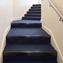 Heavy duty rake back aluminium stair nosing with black insert in satin black finish fitted on a stair with navy contract carpet