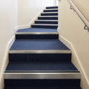 Heavy duty rake back aluminium stair nosing with black insert in mill finish finish fitted on a stair with navy contract carpet