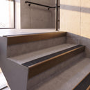 Dark Bronze rake back DDA aluminium stair nosing 70 x 56mm with Coal black Exterior Grip insert, fitted on raked concrete stairs in a commercial stairwell