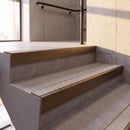 Dark Bronze rake back DDA aluminium stair nosing 70 x 56mm with Everest light grey Exterior Grip insert, fitted on raked concrete stairs in a commercial stairwell