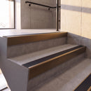 Dark Bronze rake back DDA aluminium stair nosing 70 x 56mm with Obsidian black High Grip insert, fitted on raked concrete stairs in a commercial stairwell
