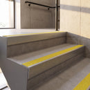 Mill Finish rake back DDA aluminium stair nosing 70 x 56mm with Brimstone yellow Exterior Grip insert, fitted on raked concrete stairs in a commercial stairwell