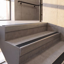 Mill Finish rake back DDA aluminium stair nosing 70 x 56mm with Coal black Exterior Grip insert, fitted on raked concrete stairs in a commercial stairwell