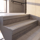 Mill Finish rake back DDA aluminium stair nosing 70 x 56mm with Everest light grey Exterior Grip insert, fitted on raked concrete stairs in a commercial stairwell