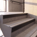 Satin Black rake back DDA aluminium stair nosing 70 x 56mm with Everest light grey Exterior Grip insert, fitted on raked concrete stairs in a commercial stairwell