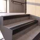 Satin Black rake back DDA aluminium stair nosing 70 x 56mm with Obsidian black High Grip insert, fitted on raked concrete stairs in a commercial stairwell
