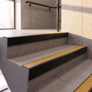 Satin Black rake back DDA aluminium stair nosing 70 x 56mm with Solar yellow High Grip insert, fitted on raked concrete stairs in a commercial stairwell