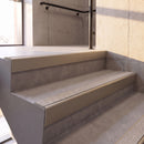 Satin Bronze rake back DDA aluminium stair nosing 70 x 56mm with Everest light grey Exterior Grip insert, fitted on raked concrete stairs in a commercial stairwell