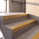 Satin Gold rake back DDA aluminium stair nosing 70 x 56mm with Solar yellow High Grip insert, fitted on raked concrete stairs in a commercial stairwell
