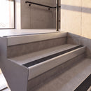 Satin Silver rake back DDA aluminium stair nosing 70 x 56mm with Coal black Exterior Grip insert, fitted on raked concrete stairs in a commercial stairwell