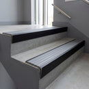 Black Anodised raked back aluminium stair nosing 62x55mm with Flint Castellated infill, fitted to a concrete step