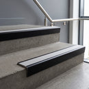 Black Anodised raked back aluminium stair nosing 62x55mm with Polar Grey Castellated infill, fitted to a concrete step