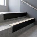 Black Anodised raked back aluminium stair nosing 62x55mm with Porth Stone Smooth Textured infill, fitted to a concrete step