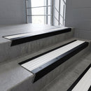Black Anodised raked back aluminium stair nosing 62x55mm with White Castellated infill, fitted to a concrete step