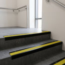 Black Anodised raked back aluminium stair nosing 62x55mm with Yellow Castellated infill, fitted to a concrete step